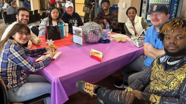 Tav with a group of friends around a table at a student life event